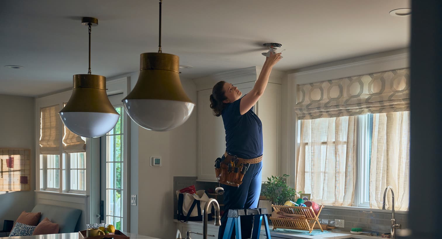 A professional Elite electrician standing on a ladder to install modern recessed ceiling lights during a residential electrical installation service.