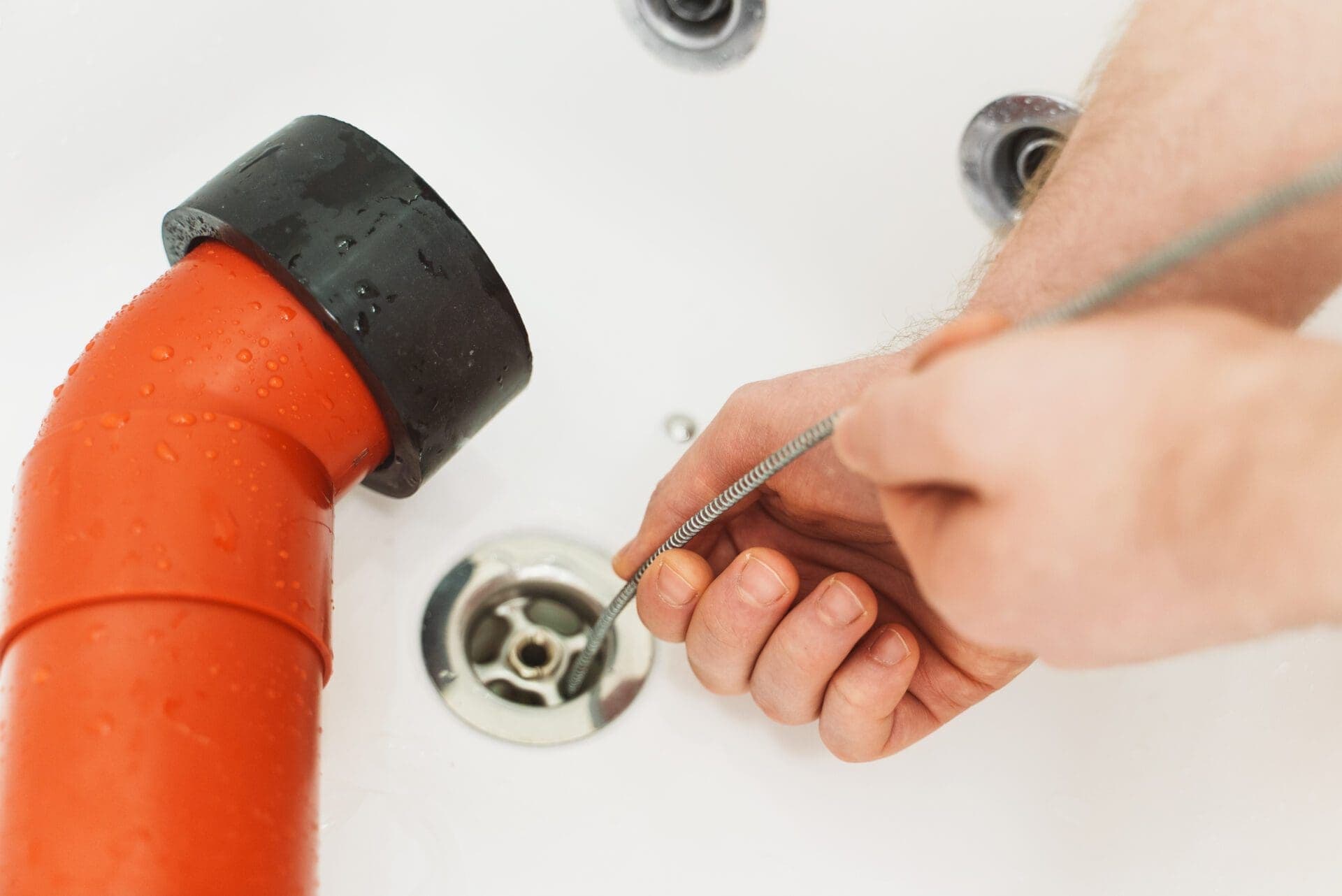 Plumber using drain snake